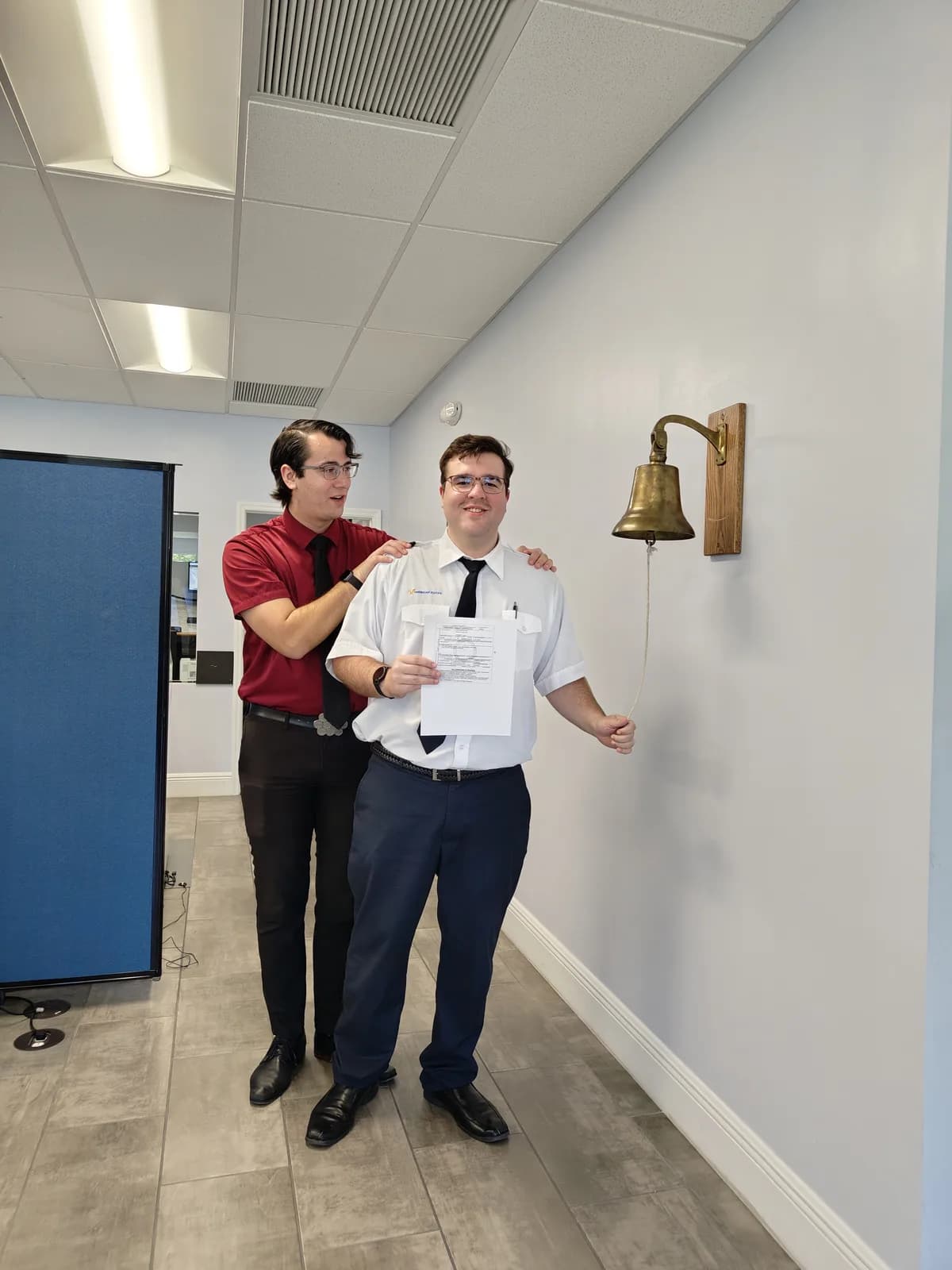 ACOM Aviation student ringing the checkride bell after passing his private pilot test