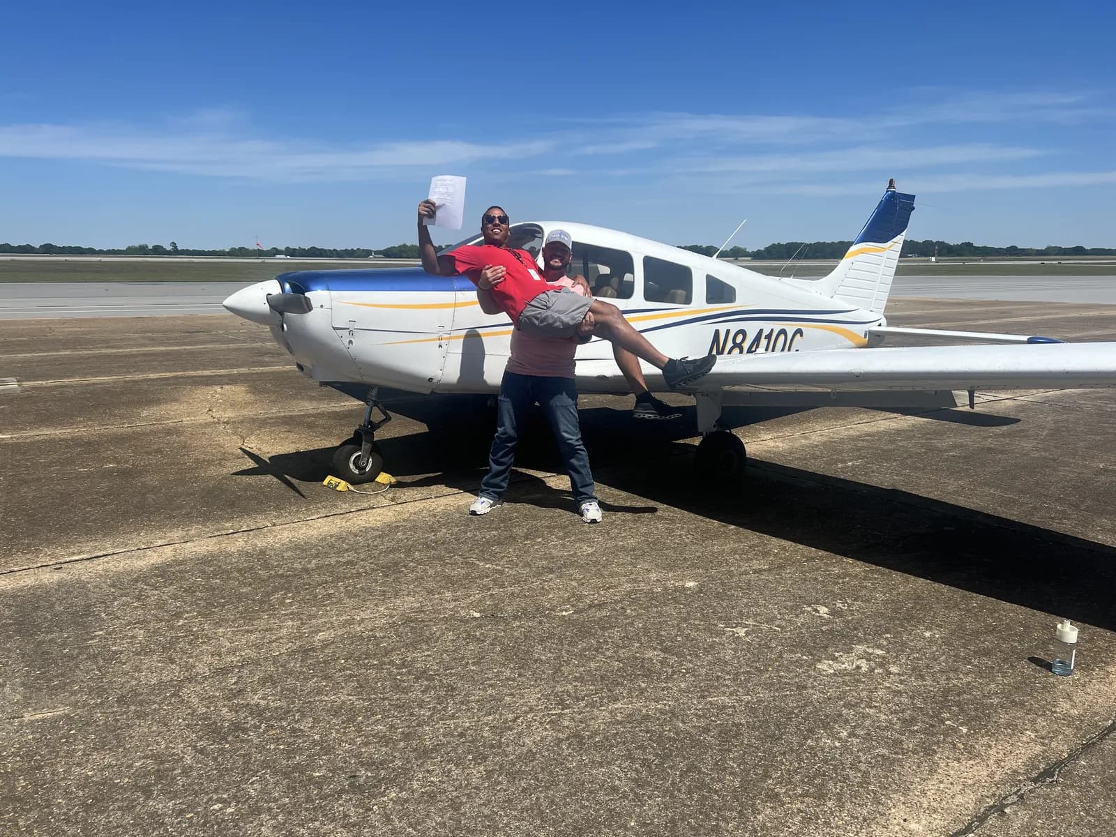 Joyful checkride celebration in front of a Piper Cherokee N8410C at Ozark-Blackwell