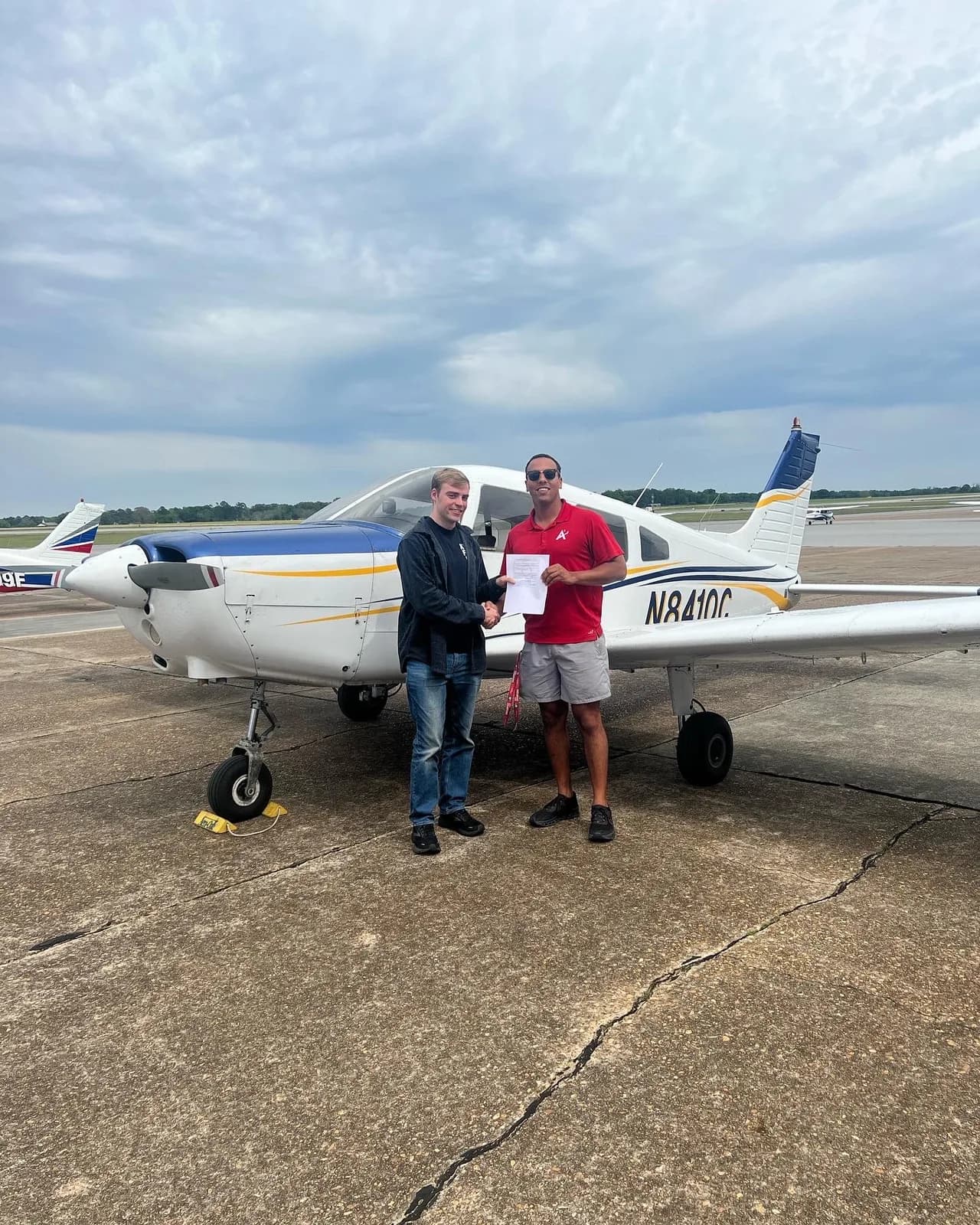 ACOM student receiving certificate in front of Cherokee on a cloudy day at 71J