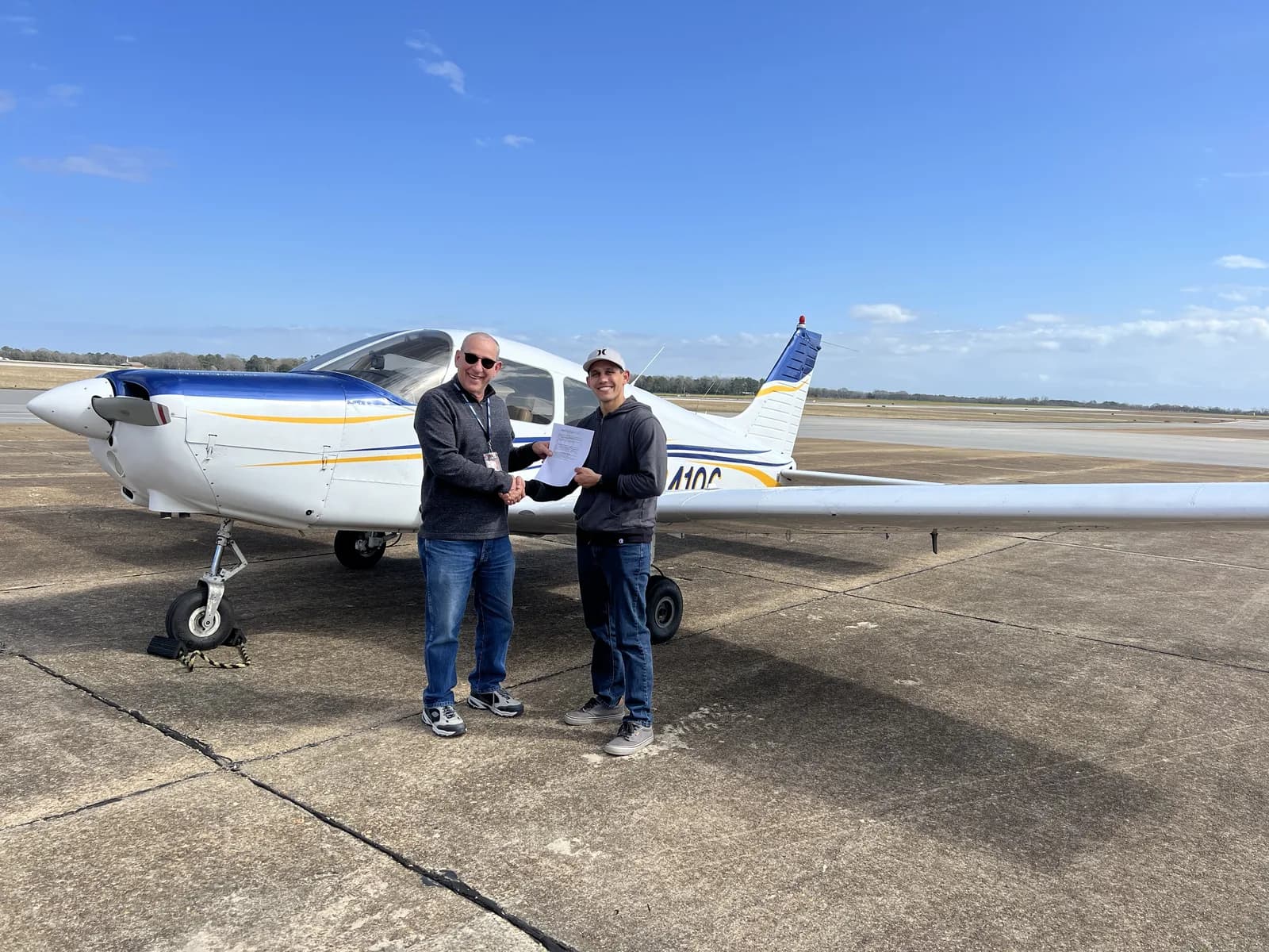 Student receiving their pilot certificate in front of a Piper Cherokee at 71J