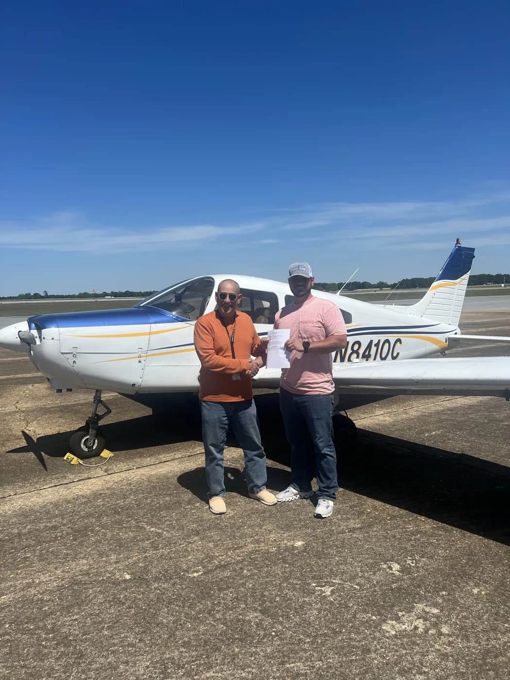 Two ACOM students celebrating in front of Piper Cherokee N8410C after a checkride at Ozark-Blackwell