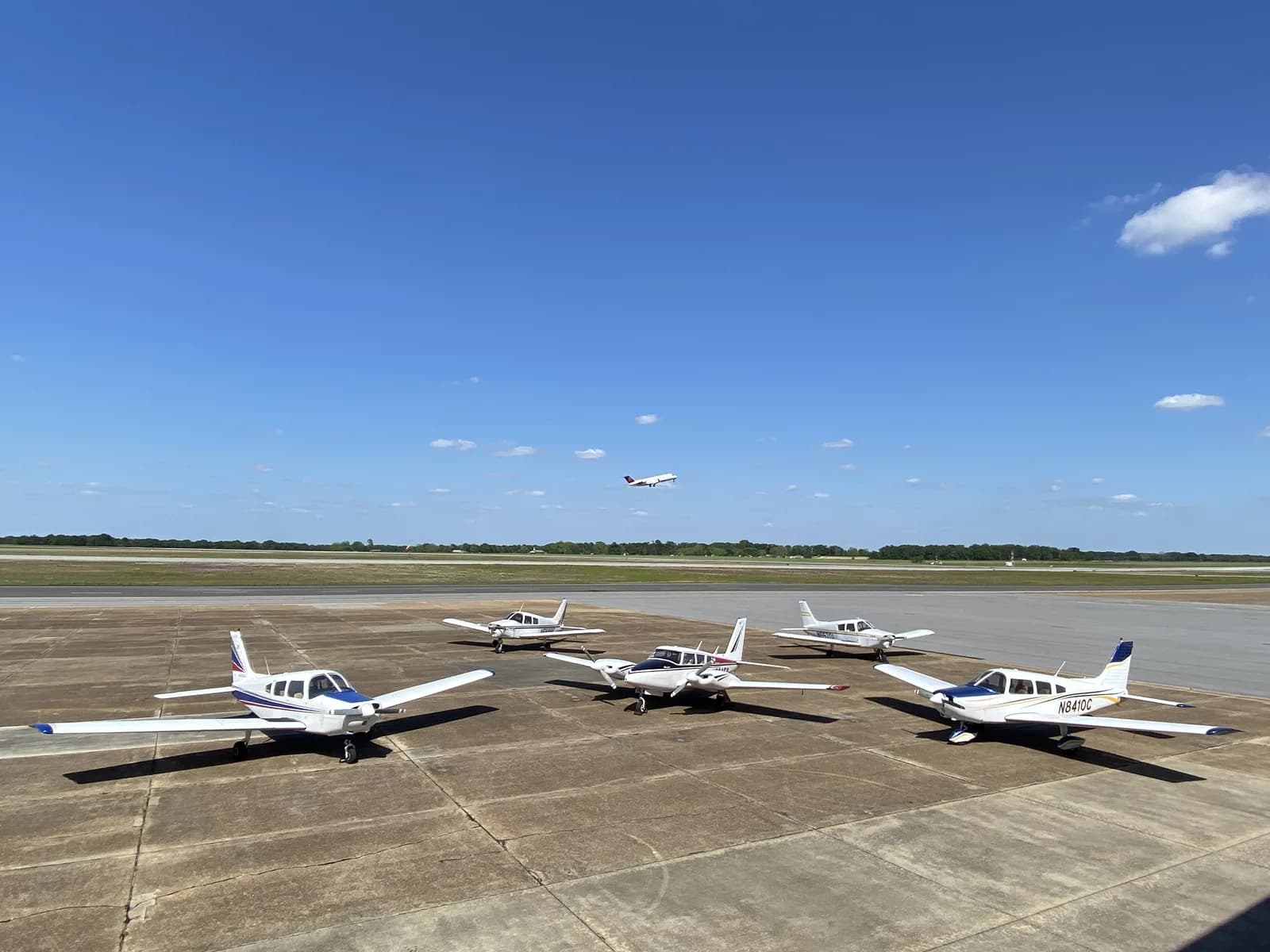 Six Piper Cherokees on the ramp with an aircraft taking off behind, Ozark-Blackwell Airport (71J)